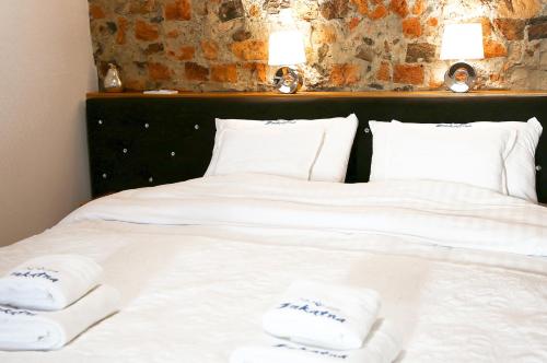 a bed with white sheets and towels on it at Aparthotel Zakątna B&B in Tarnów