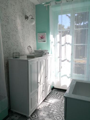 une cuisine avec une armoire blanche et une fenêtre dans l'établissement maison courbarien, à Saint-Georges-la-Pouge