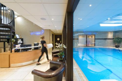 a woman walking by a swimming pool in a building at Best Western Plus The Connaught Hotel and Spa in Bournemouth