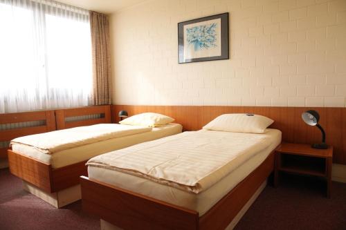 two beds in a hotel room with a window at RTB-Hotel - Sportschule in Bergisch Gladbach