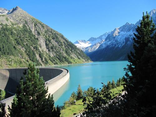 a dam on a lake with mountains in the background at Hotel Englhof in Zell am Ziller