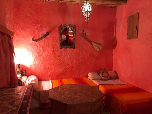 a red room with two beds and a mirror at Auberge Chez Julia in Merzouga