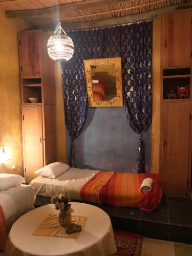 a room with two beds and a table and a chandelier at Auberge Chez Julia in Merzouga