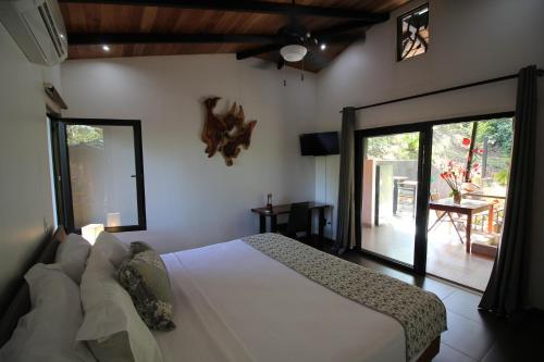 a bedroom with a white bed and a sliding glass door at Oasis de las Palmas in Ojochal