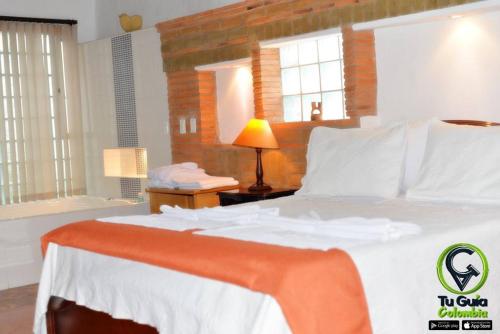 a bedroom with a white bed with a lamp and windows at Hotel Los Frayles in Villa de Leyva