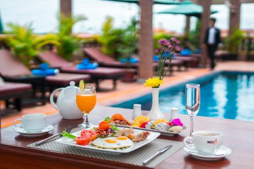 a table with breakfast food and drinks and a swimming pool at Hello Cambodia Boutique in Siem Reap
