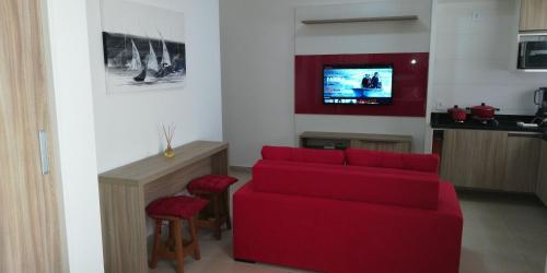 a living room with a red couch and a tv at Flats Dunas Cabo Frio in Cabo Frio