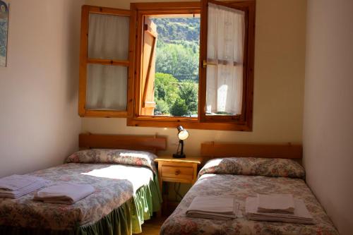 two beds in a room with a window at Apartamentos Ball Benas Benasque in Benasque