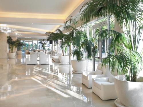 a lobby with white chairs and palm trees at Grand Beach Hotel in Miami Beach