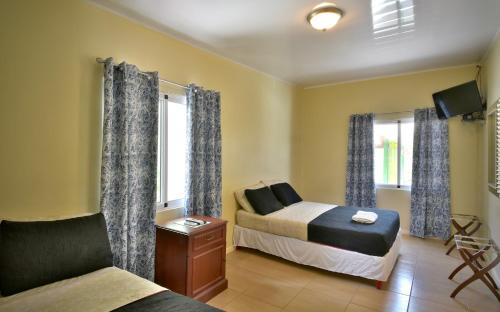 a bedroom with a bed and a couch and windows at Pista Q hostel and apartments in Oranjestad