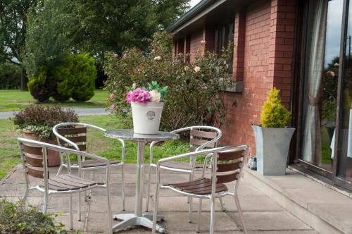 a table with chairs and a vase of flowers on it at The Old Schoolhouse Inn in Comber