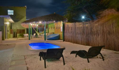 a backyard with a swimming pool and two chairs and a fence at Pista Q hostel and apartments in Oranjestad