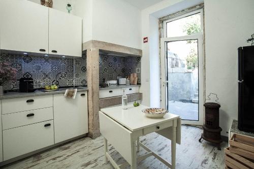 a white kitchen with a table and a window at Casa Velha in Alenquer