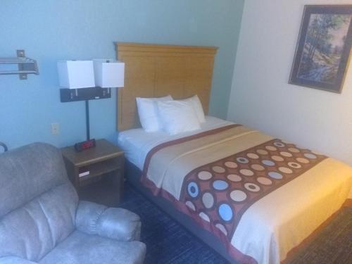 a hotel room with a bed and a chair at Super 8 by Wyndham Baxter/Brainerd Area in Baxter