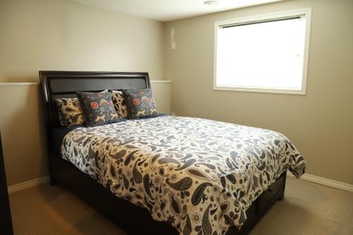 a bedroom with a bed with a comforter and a window at Sweet Home In Calgary in Calgary