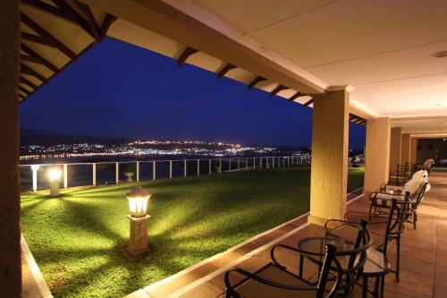 a patio with tables and chairs on a balcony at night at Villa Castollini in Brenton-on-Sea