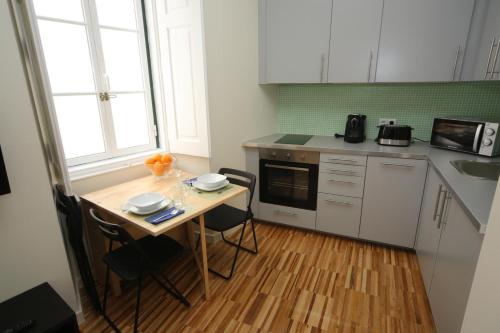 een keuken met een tafel met stoelen en een magnetron bij Casa de Santa Marta in Lissabon