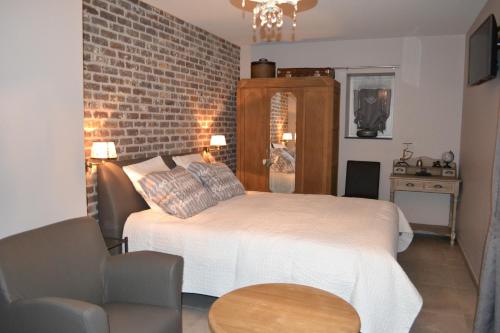 a bedroom with a bed and a brick wall at B&B 't Heirweggoed in Assenede
