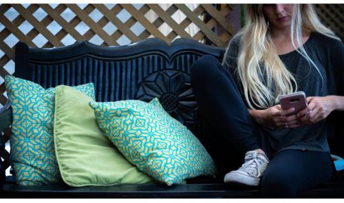 a woman sitting on a couch with a cell phone at Hostal Guatefriends in Guatemala