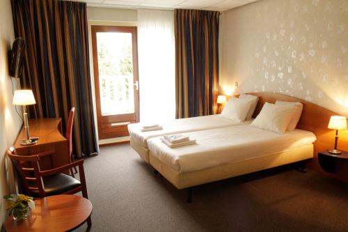 a hotel room with a bed and a window at De Vooroever in Wervershoof