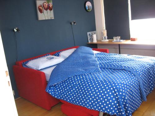 a bed with blue and white polka dot sheets on it at De Krasse Man in Edam