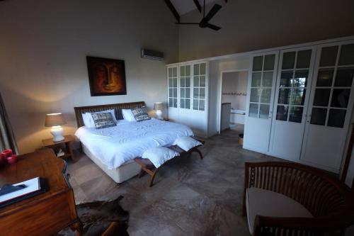 a bedroom with a bed and a desk and a table at Thatch by the Sea in Blythedale
