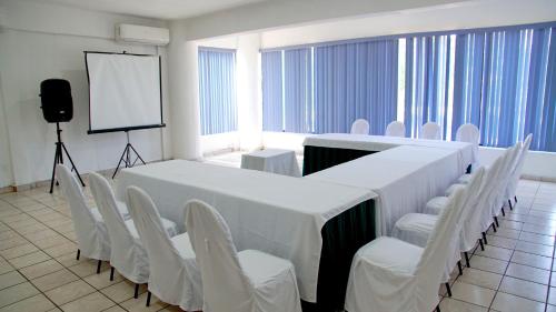 a conference room with a long table and white chairs at Hotel Costa Brava in Manzanillo