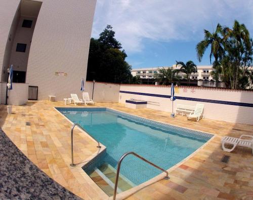 a swimming pool with chairs and a building at Ubatuba - Praia do Itagua in Ubatuba
