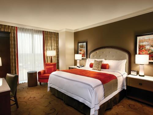 a hotel room with a large bed and a chair at L'Auberge Baton Rouge in Baton Rouge