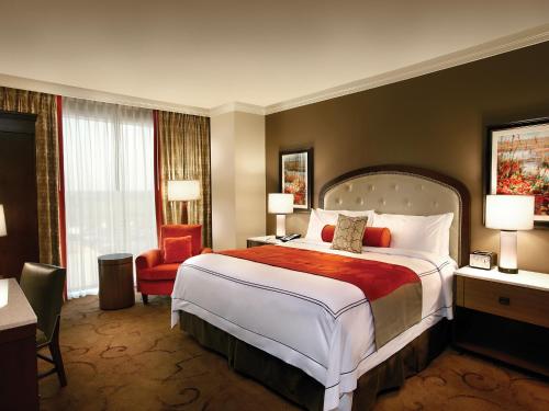 una camera d'albergo con un grande letto e una sedia di L'Auberge Baton Rouge a Baton Rouge