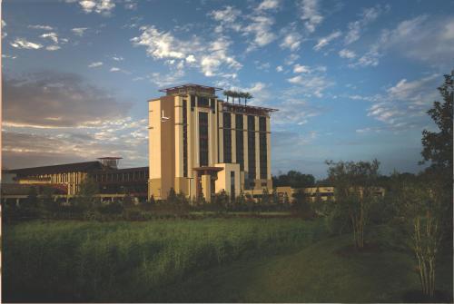 a large building with a tower in front of a field at L'Auberge Baton Rouge in Baton Rouge