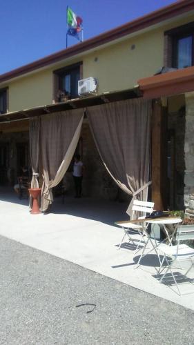 a building with curtains and chairs in front of it at Agriturismo La Vallata in Masseria Scilva