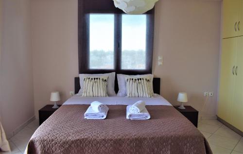 a bedroom with a large bed with two towels on it at Luxury Apt Near The Airport in Spata