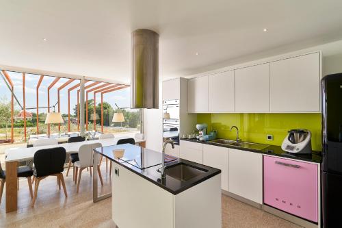 a kitchen with white cabinets and a dining room at Oliveira House in Castelo Novo