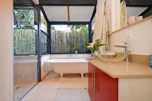 a bathroom with a bath tub and a sink at Bamboo Cottage in Johannesburg