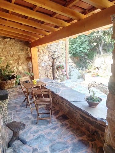 a patio with a table and chairs under a wooden roof at REFÚGIO DO RAPOSO/CASA VEGA in Montes da Senhora
