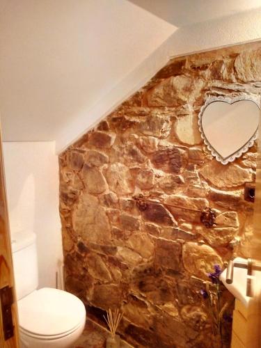 a bathroom with a stone wall with a heart shaped mirror at REFÚGIO DO RAPOSO/CASA VEGA in Montes da Senhora
