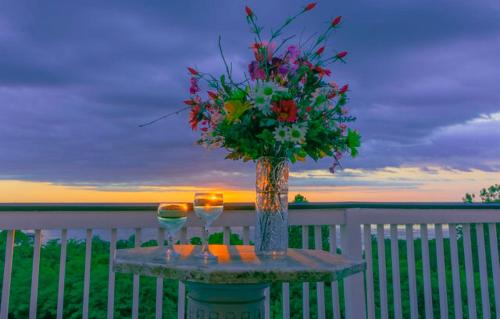 einen Tisch mit zwei Gläsern und eine Vase mit Blumen in der Unterkunft Weymouth Hall in Natchez