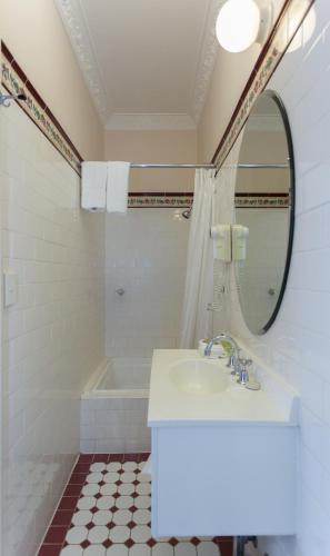 a bathroom with a sink and a mirror and a tub at Palais Royale in Katoomba