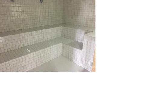a bathroom with white tiles on the floor and a tub at Apto pé-na-areia em Bertioga - Indaia Home Club in Bertioga