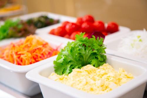 a table topped with three trays of food with vegetables at Hotel Bellclassic Tokyo in Tokyo