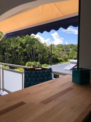 a balcony with a wooden table and a view of trees at Tigili l'Appart Lagon in Capesterre-Belle-Eau