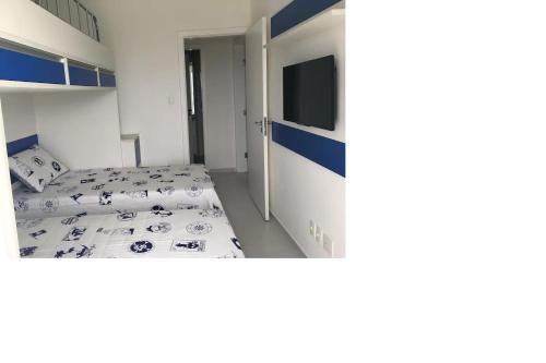 a small room with two beds and a television at Apto pé-na-areia em Bertioga - Indaia Home Club in Bertioga