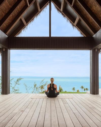 a woman sitting on a deck looking out at the ocean at Six Senses Fiji in Malolo