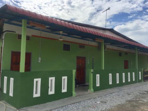 a green building with a red roof at Bunga Raya Guest House BALING in Baling