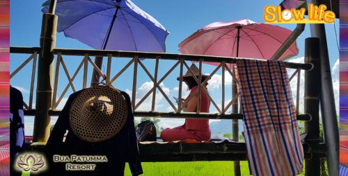 a person is sitting in a chair with umbrellas at Bua Patumma Resort in Mae Sai