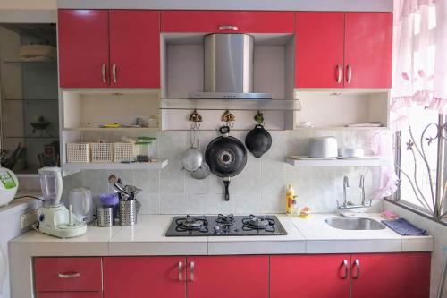 a kitchen with red cabinets and a stove top oven at Homestay Jasmin Indah, Senawang (free wifi) in Seremban