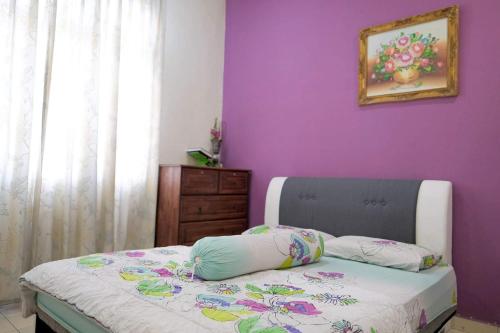 Schlafzimmer mit lila Wänden und einem Bett mit Kissen in der Unterkunft Homestay Jasmin Indah, Senawang (free wifi) in Seremban