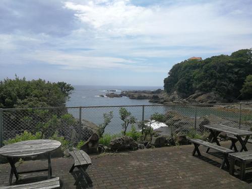 a patio with two picnic tables and a view of the ocean at 海のお宿 in Susami
