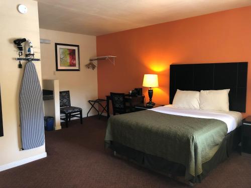 a hotel room with a bed with an orange wall at Arroyo Village Inn in Arroyo Grande